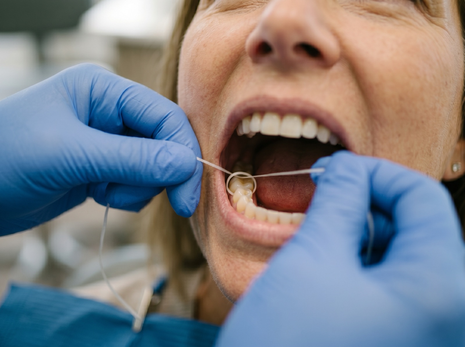 A demonstration of correct flossing technique, clean hands guiding floss in a U-shape between teeth